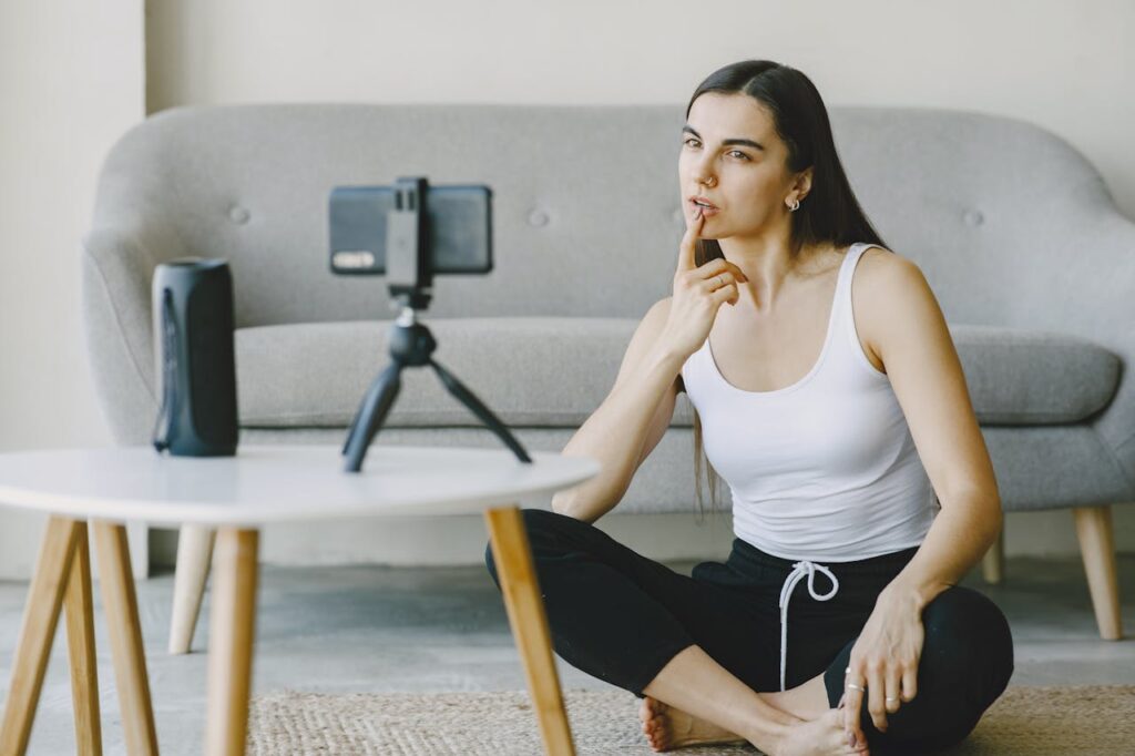 A woman vlogging indoors, seated on the floor with a smartphone, showcasing a modern lifestyle setup.